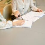 Creative Financing in Real Estate: Exploring New Options for Investors in Florida woman signing on white printer paper beside woman about to touch the documents